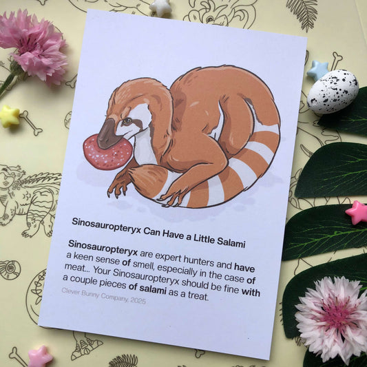 An art print of an illustration of a Sinosauropteryx dinosaur holding a slice of salami. The text below reads “Sinosauropteryx can have a little salami”. “Sinosauropteryx are expert hunters and have a keen sense of smell, especially in the case of meat…Your Sinosauropteryx should be fine with a couple pieces of salami as a treat. Clever Bunny Company, 2025.”